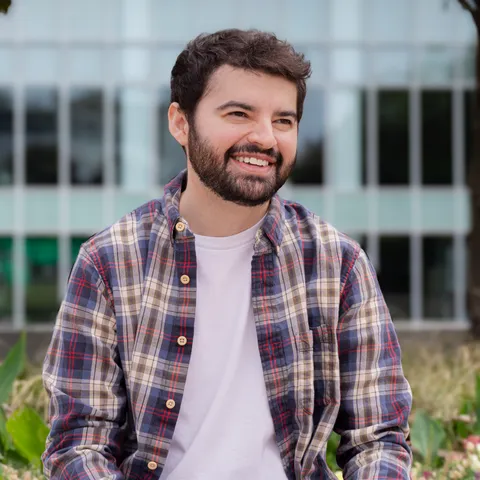 Phillip Hirsch smiling in a plaid button-up shirt and a white t-shirt